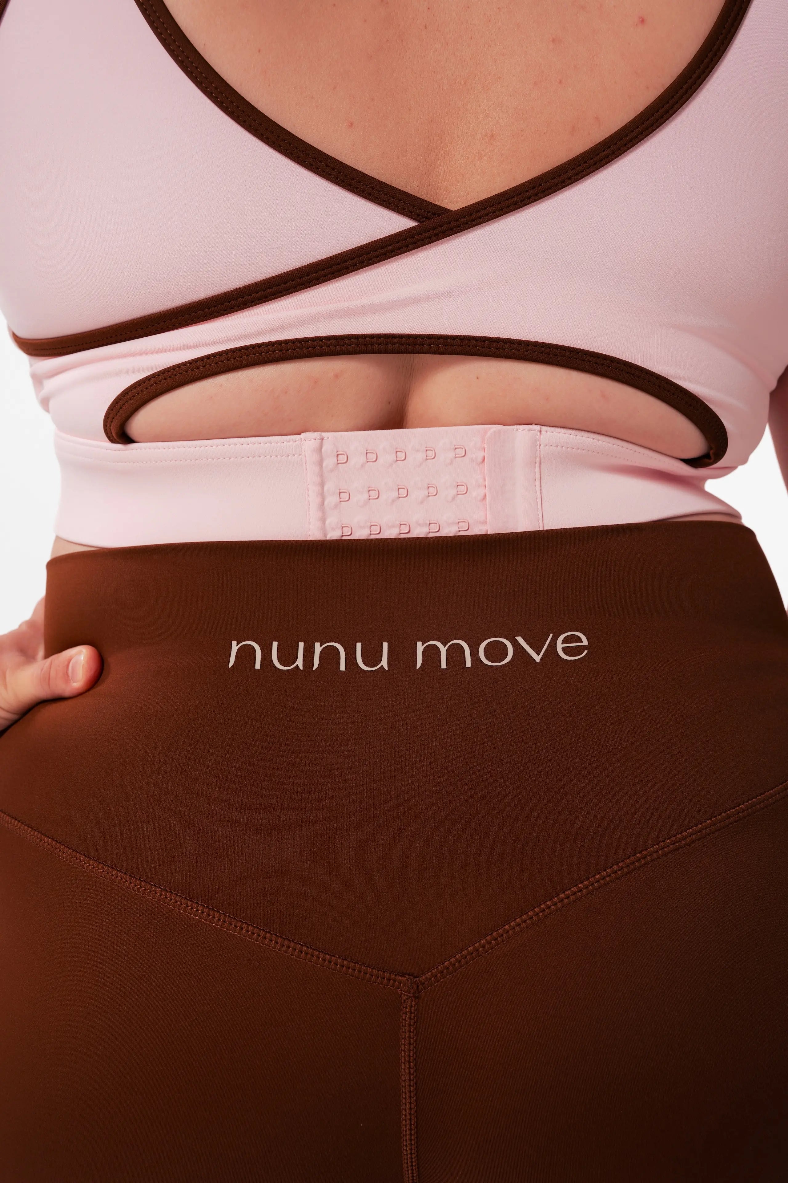 Close-up of the Nunu Move Cherry Blossom Asta nursing bra's wide multi-row hook-and-eye back clasp, above the Espresso brown V-Bum shorts waistband.