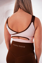 Back view of the Nunu Move Cherry Blossom nursing bra showing the crossover straps and multi-row adjustable back clasp, worn with Espresso brown V-Bum shorts.